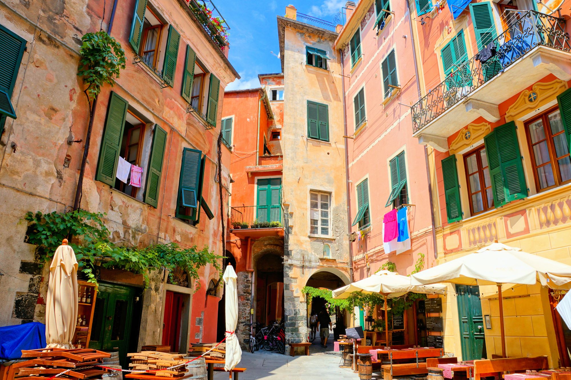 Trg v kraju Monterosso, eni od petih vasic Cinque Terre, s hišami s pisanimi fasadami in letnimi vrtovi restavracij.