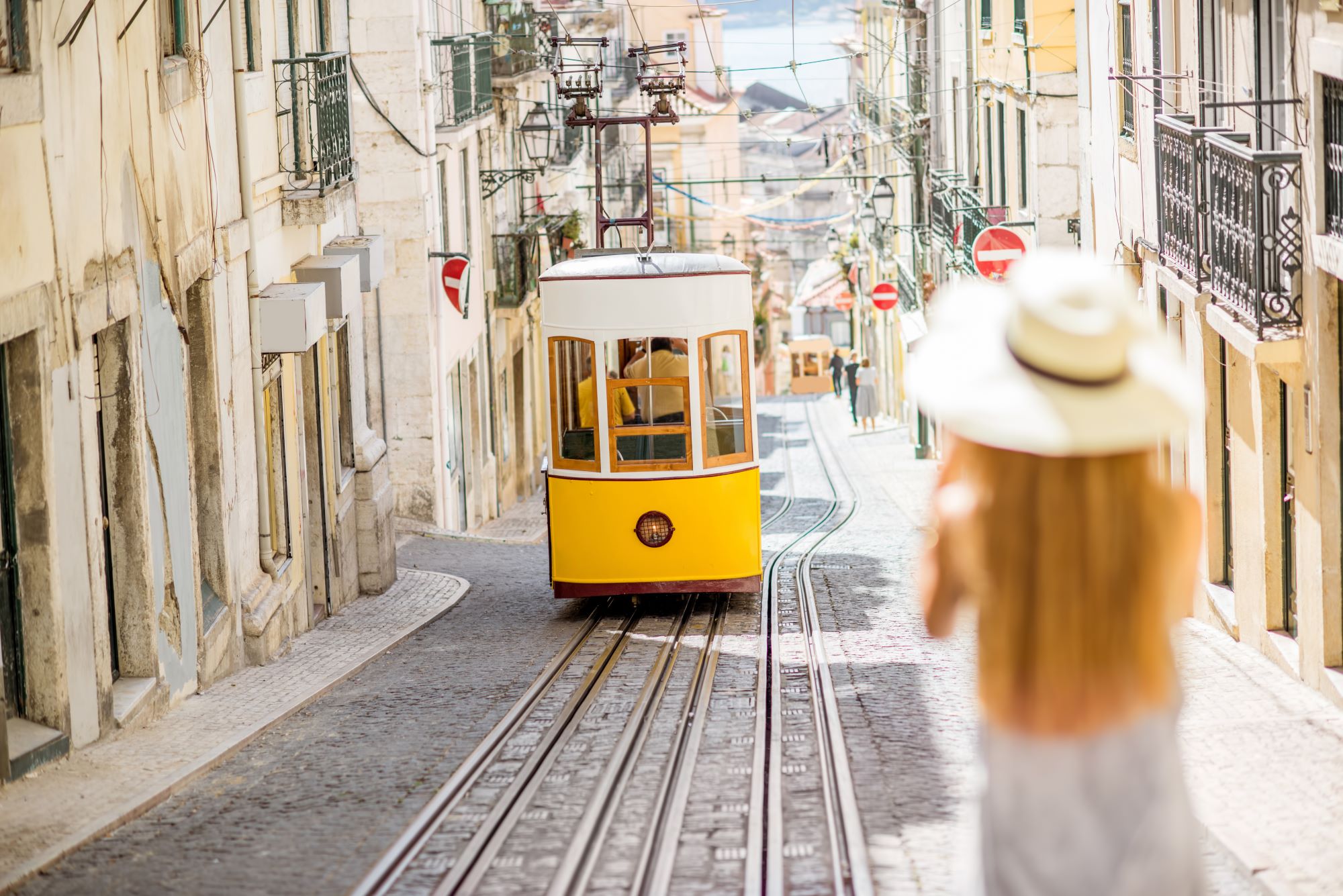 Rumeni tramvaj se vzpenja po ulici v starem delu Lizbone na Portugalskem.