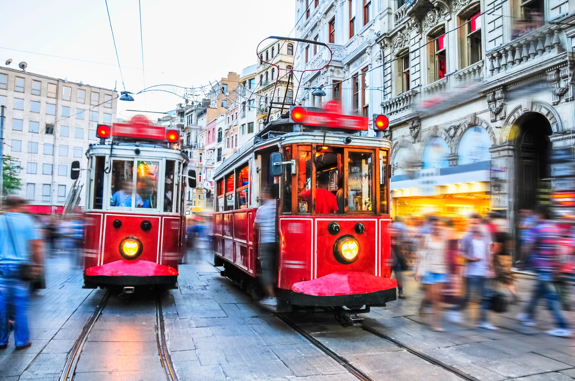 Živahen moderen trg Taksim v Istanbulu z množico domačinov in turistov in tramvajem.