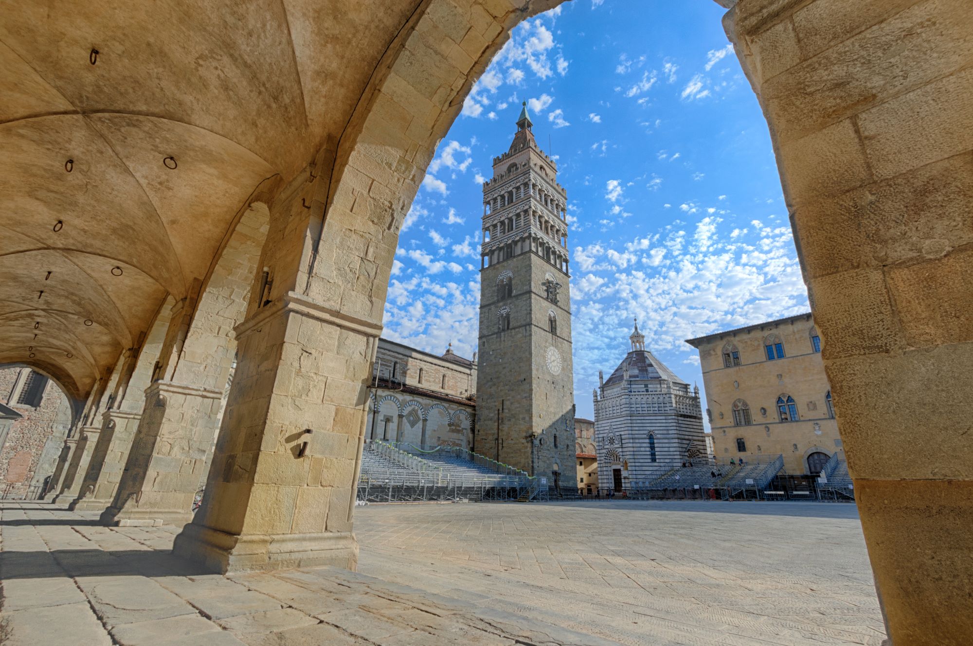 Pogled na trg Piazza del Duomo v Pistoii s katedralo, zvonik in krstilnico skozi arkade mestne hiše.