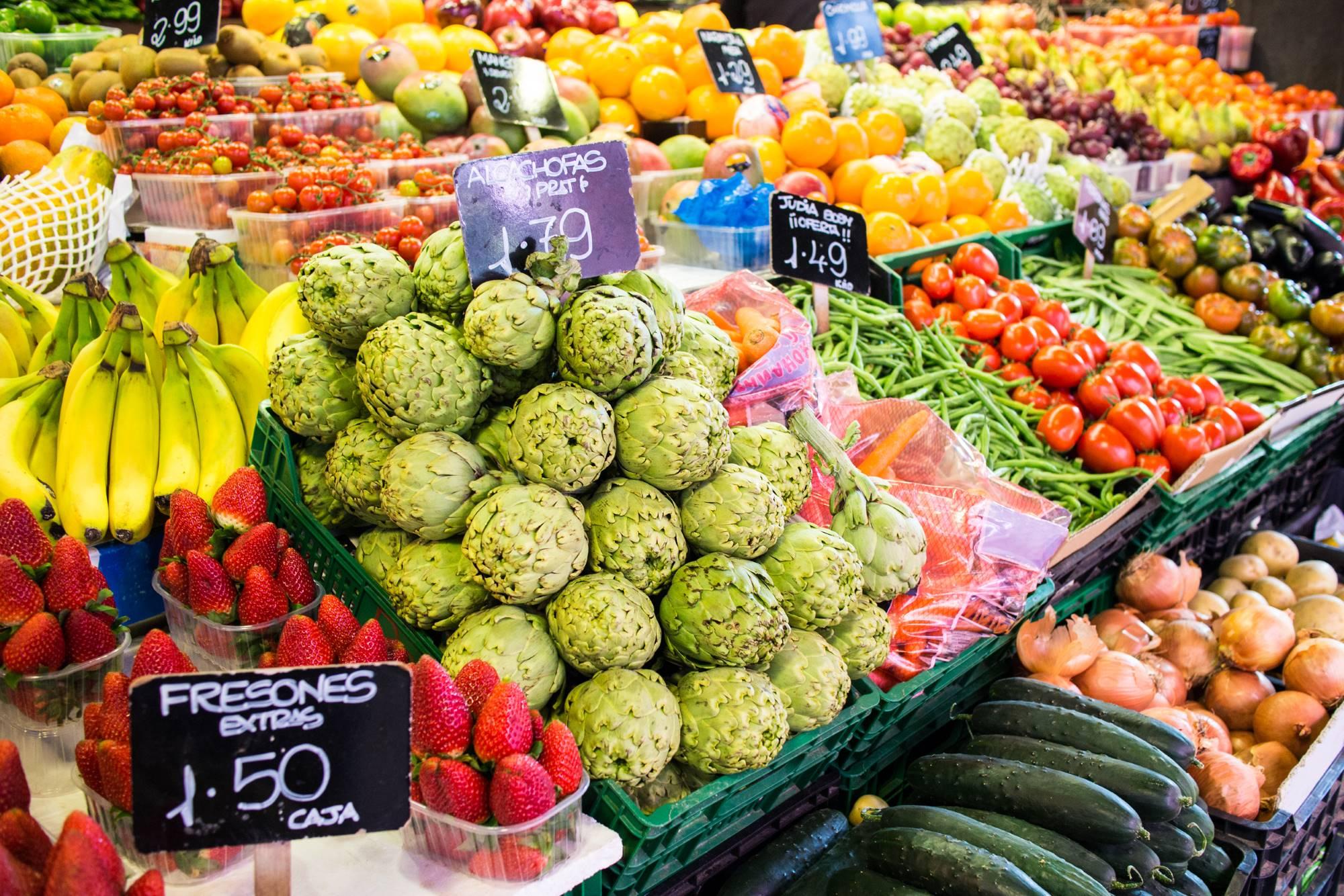 Raznovrstno sadje in zelenjava, od artičok in različnih vrst paradižnika do pomaranč in jagod, na pokriti tržnici La Boqueria v središču Barcelone.