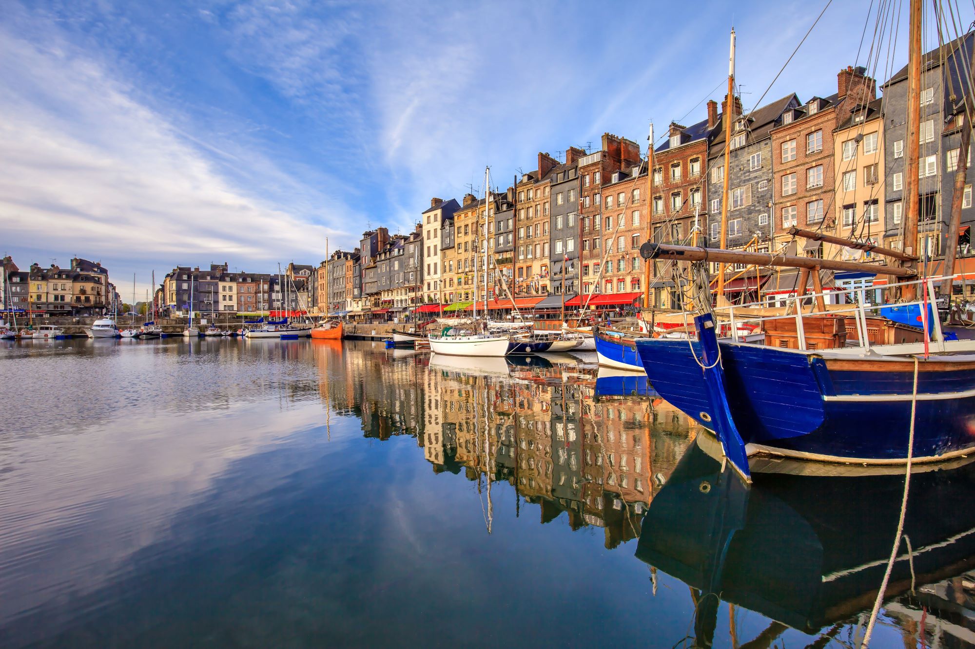 Marina in obalna promenada s pisanimi hišami v slikovitem mestecu Honfleur v Normandiji.