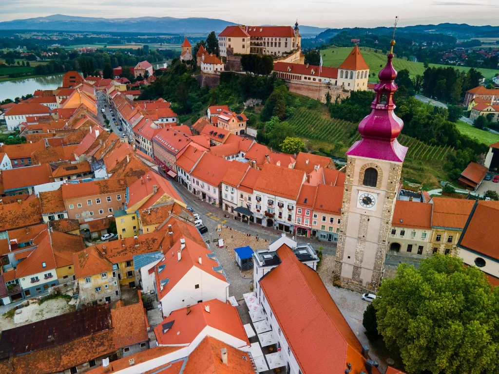 Pogled iz zraka na staro mestno jedro najstarejšega slovenskega mesta Ptuja s Prešernovo ulico, cerkvijo svetega Jurija in Ptujskim gradom, ki se dviga nad mestom.