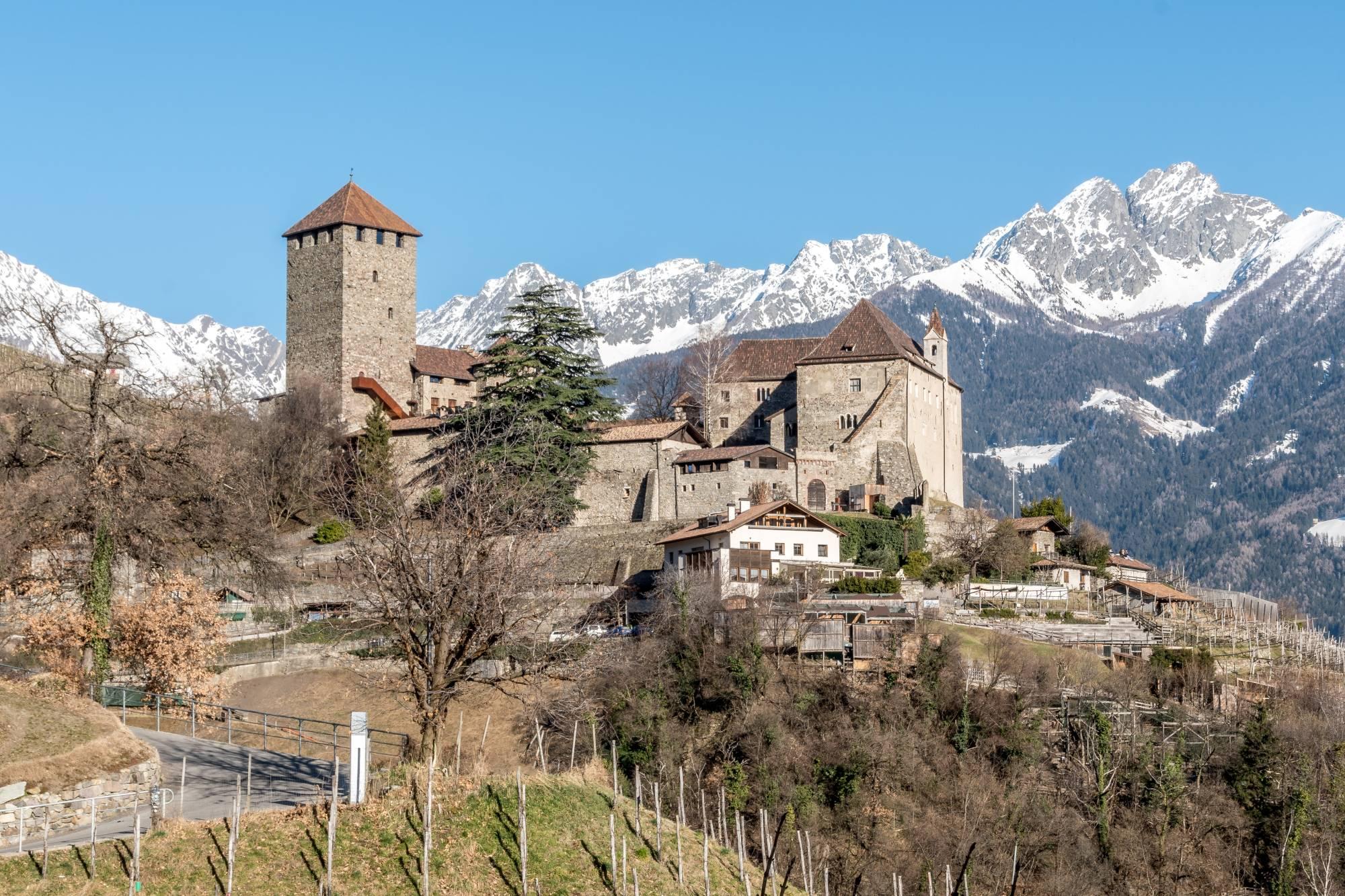 Grad Tirol v Meranu in v ozadju zasneženi vrhovi Dolomitov.