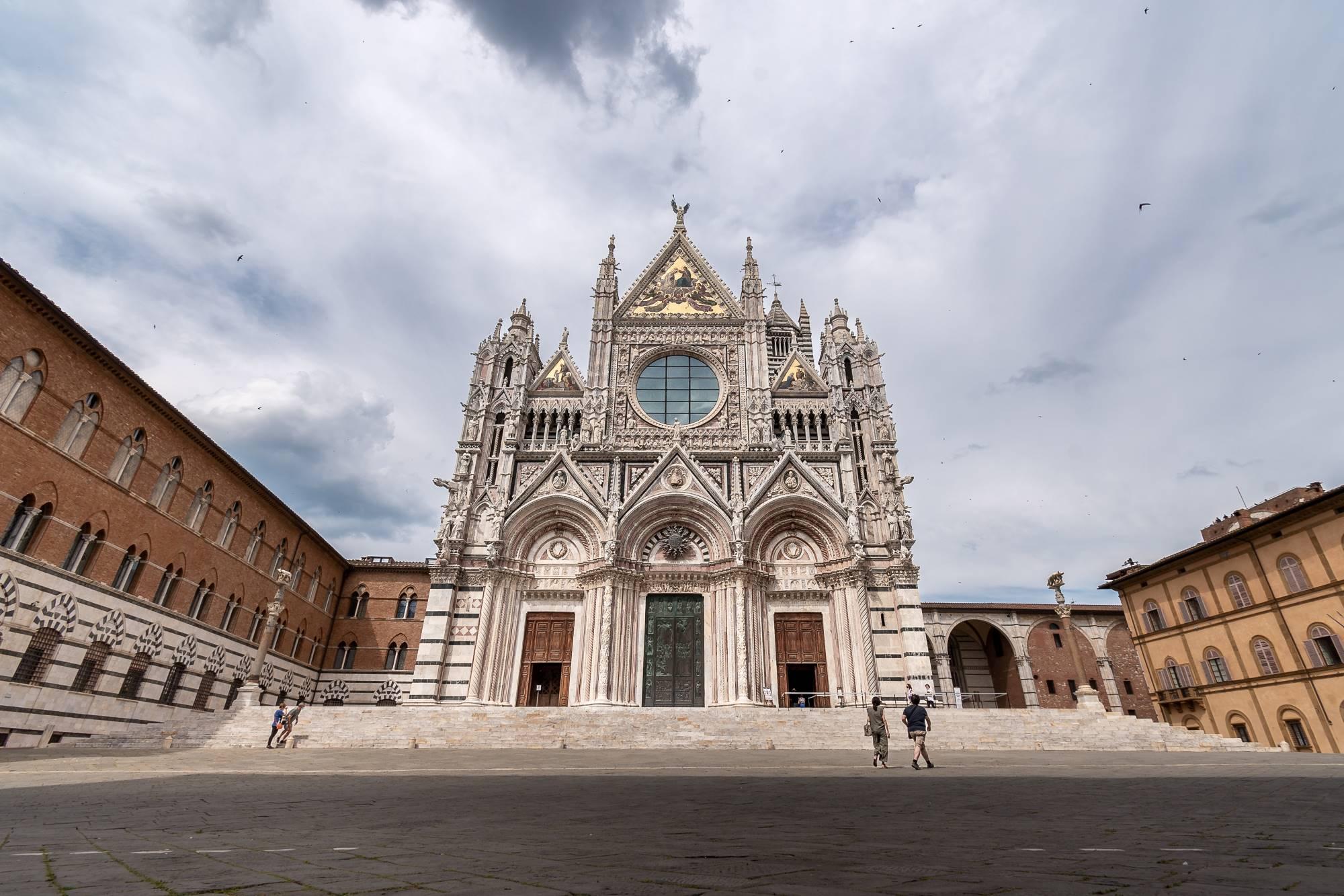 Glavna fasada sienske gotske katedrale na trgu Piazza del Duomo v Italiji.