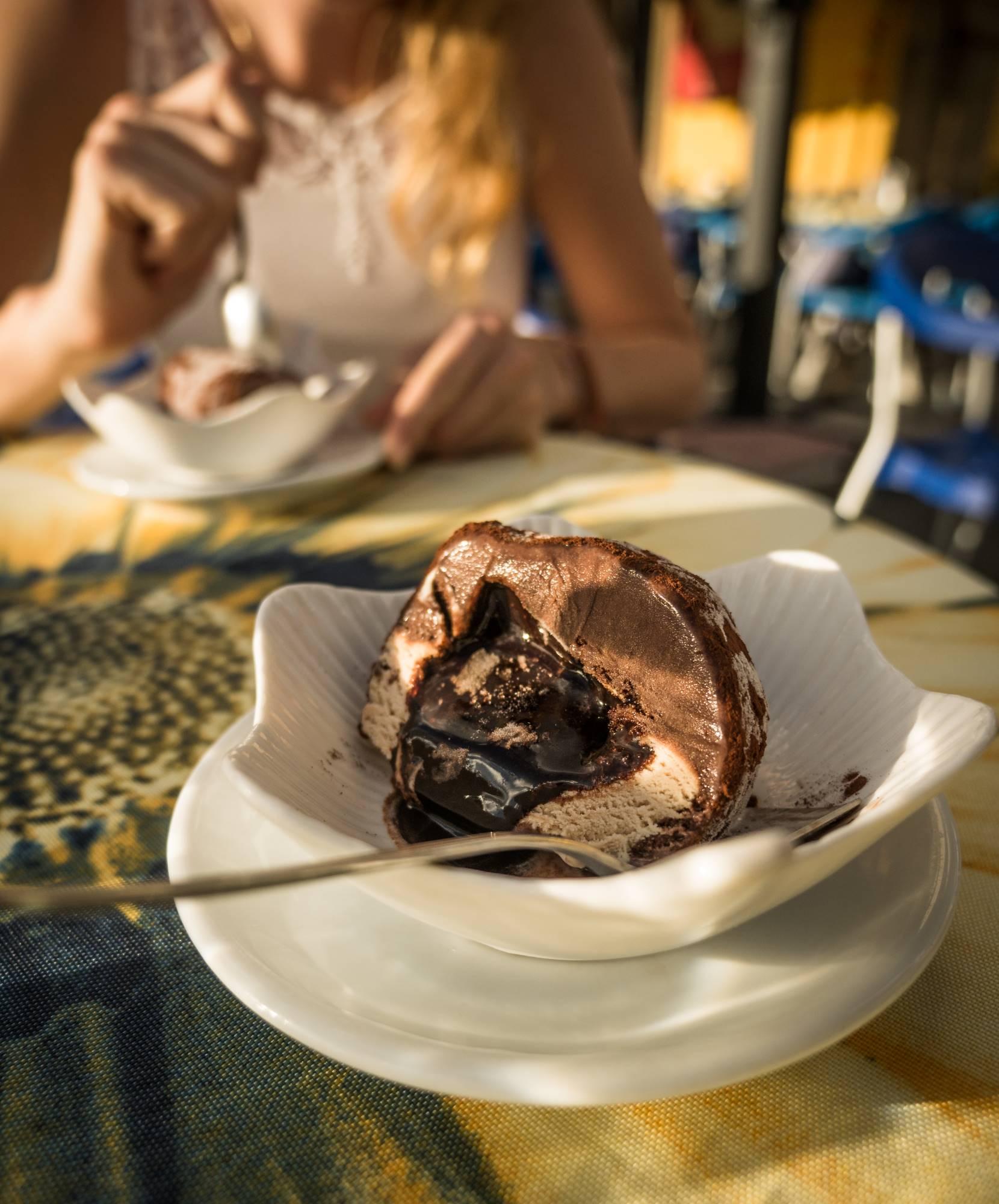 Par v kalabrijskem baru uživa v značilni sladici Tartufo di Pizzo iz čokoladnega in lešnikovega sladoleda s čokoladnim prelivom in karameliziranimi lešniki.