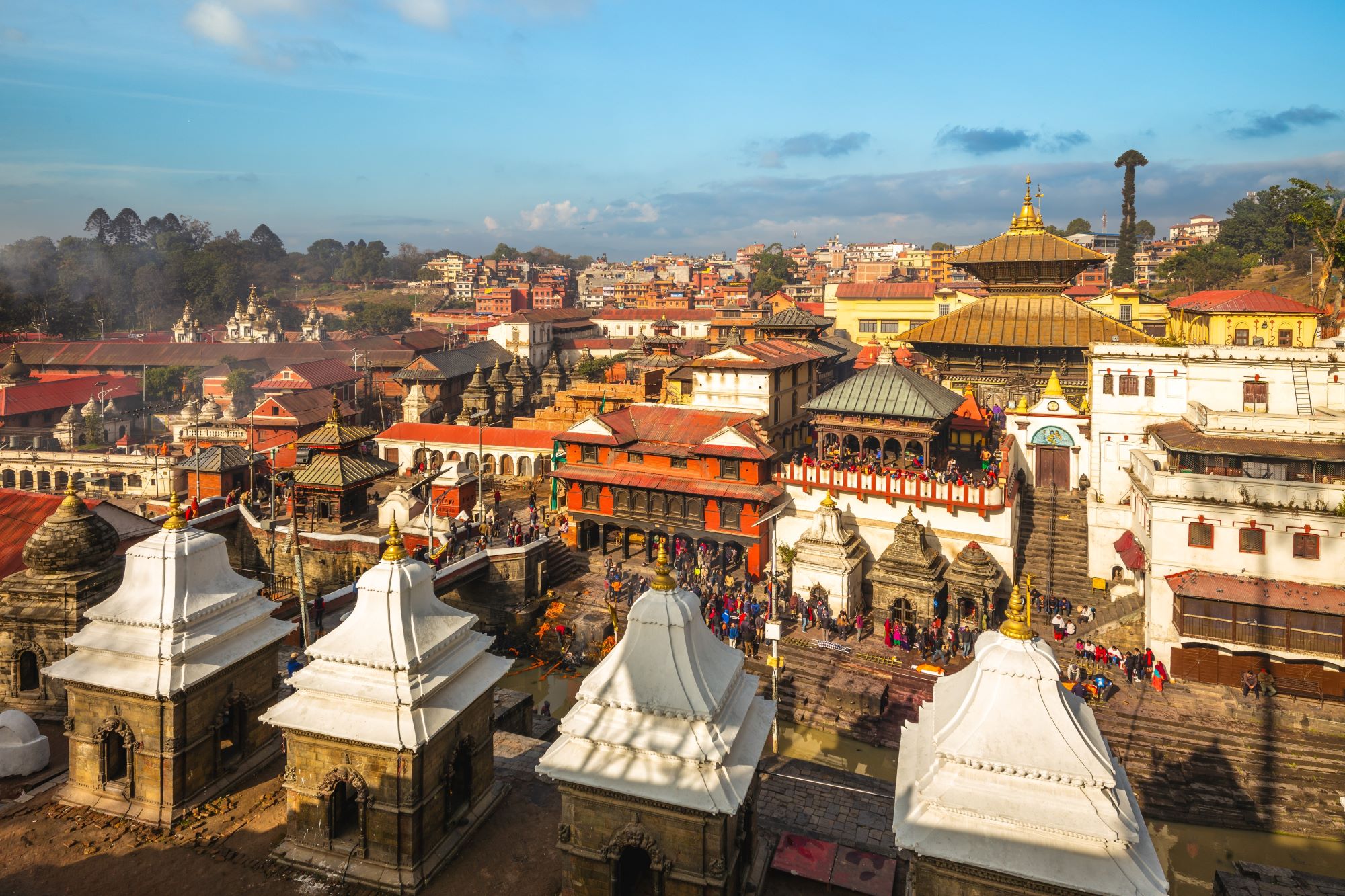 Pogled na mesto Pashupatinath v Katmandujski dolini v Nepalu s sveto reko Bagmati, kjer potekajo hindujski obredi sežiganja pokojnikov, in številnimi templji.