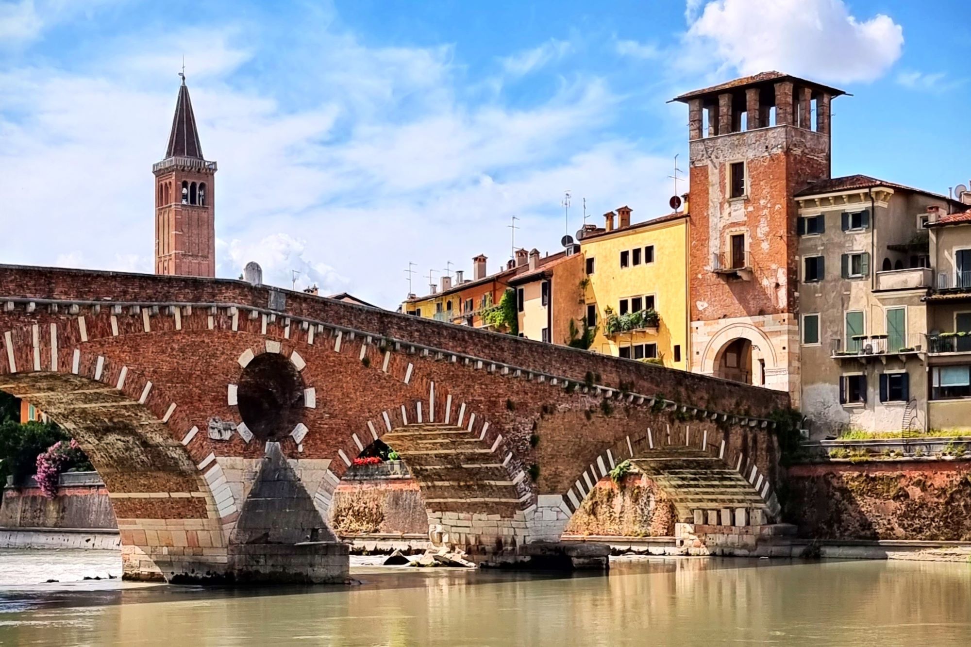 Most Ponte Pietra, ki se pne nad reko Adižo, in istoimenski stolp, ki predstavlja vhod v staro mestno jedro Verone.