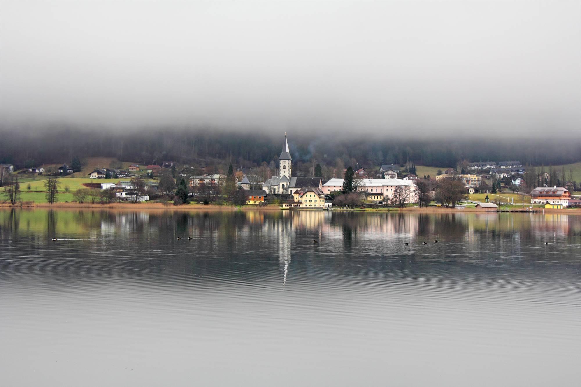 Ledeniško Osojsko jezero in opatija Osoje med strmimi pobočji Osojščice in zahodnim vznožjem Osojskih Tur v Avstriji.