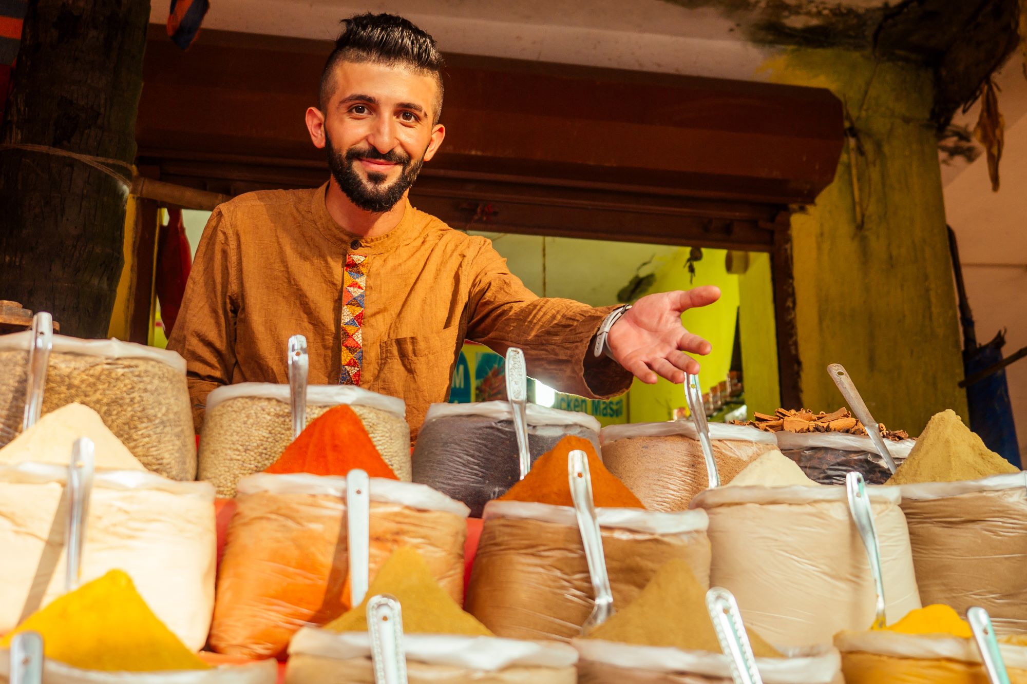 Prodajalec v tradicionalnem indijskem oblačilu ponuja začimbe s svoje stojnice.