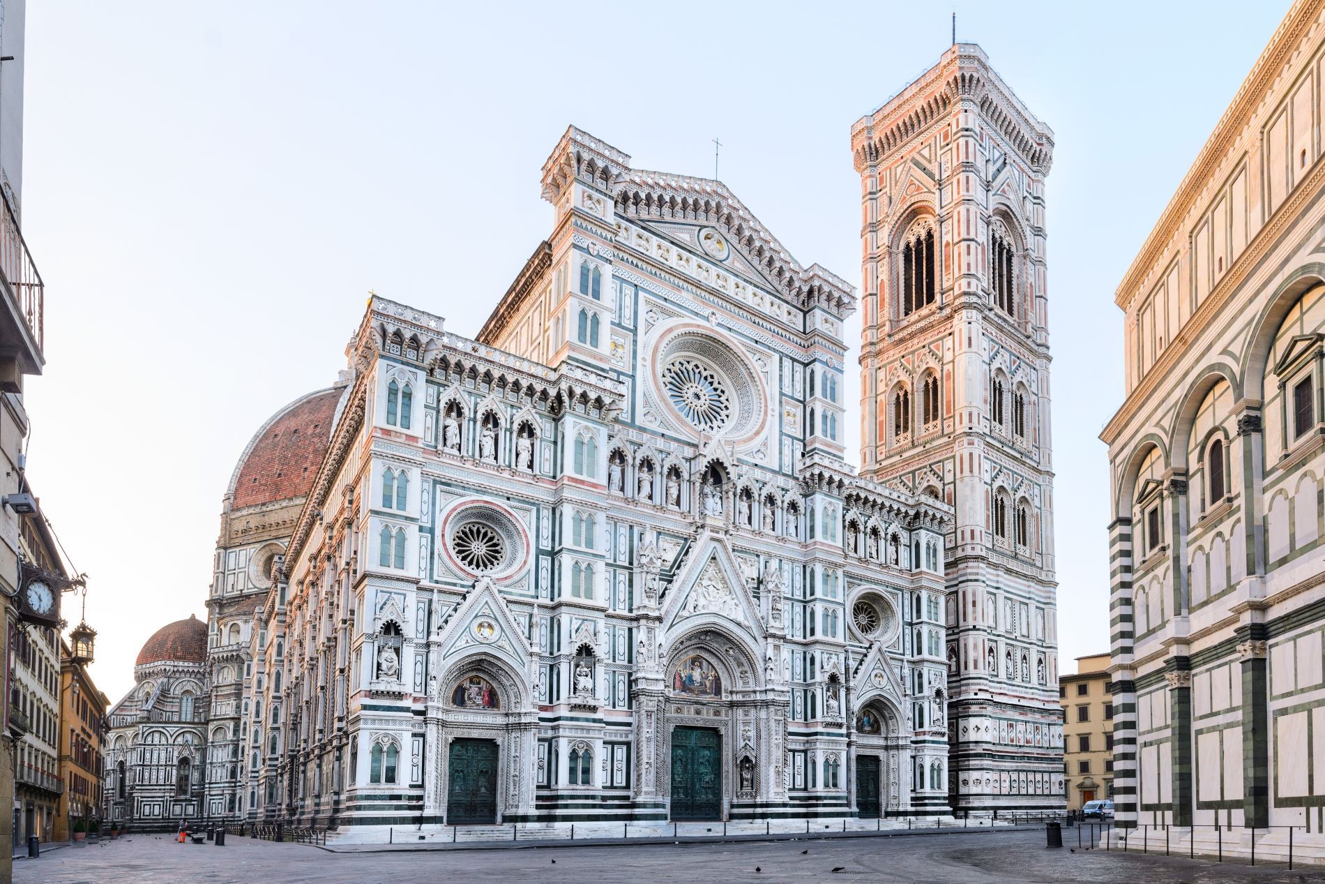 Osrednji firenški trg Piazza del Duomo v jutranji svetlobi brez ljudi s pogledom na neogotsko glavno fasado stolnice in stolp campanille.