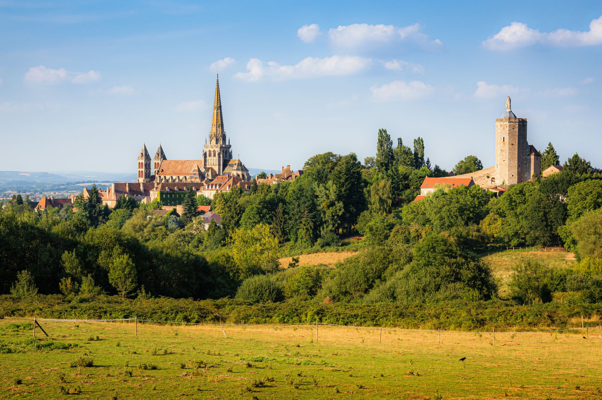 Pogled na mestece Autun z mogočno romansko stolnico Saint Lazare in zeleno pokrajino Burgundije v Franciji.