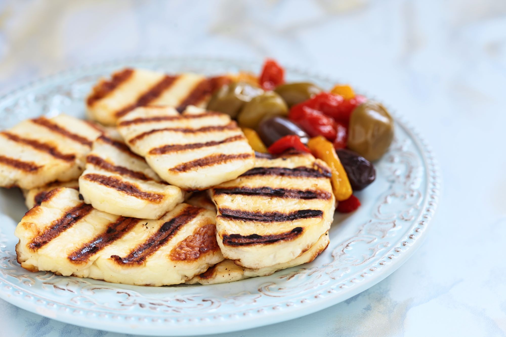 Značilni ciprski sir halloumi, postrežen na krožniku z olivami in papriko.