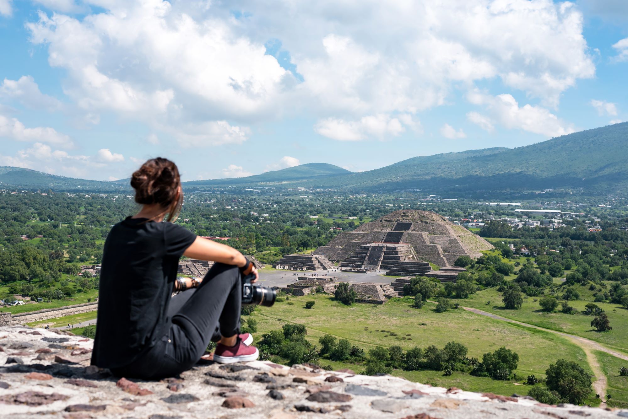 Turistka z vrha piramide Lune opazuje ostanke nekdanjega velemesta Teotihuacan v Mehiki s piramido Sonca na koncu.
