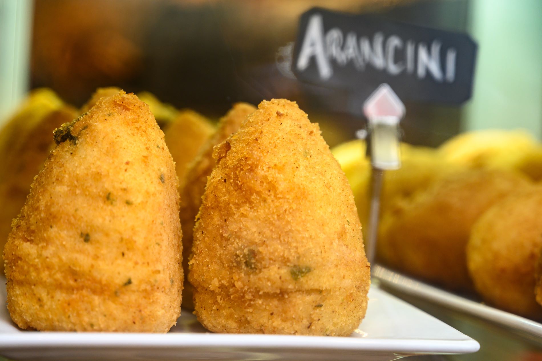 Bližnji posnetek sicilijanskih prigrizkov arancinov, paniranih ocvrtih polnjenih riževih kroglic.