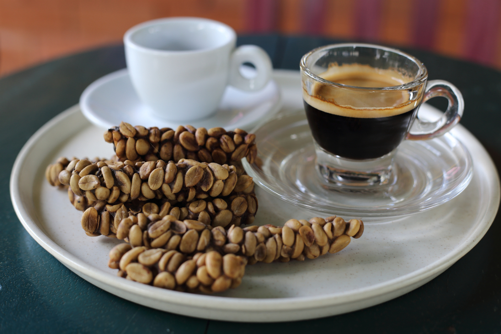 Zrna kave kopi luwak in skodelica kave na belem krožniku.