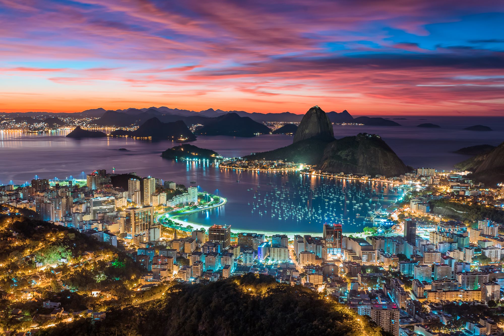 Panoramski pogled na osvetljeni center Ria de Janeira ponoči z goro Sladkorni stožec in zaliv Guanabara.