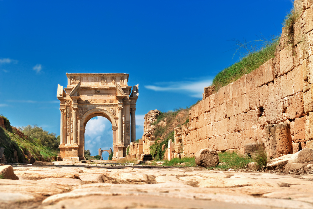 Kamnita pot z zidom, ki vodi do ostankov antičnega slavoloka v rimskem mestu Leptis Magna.