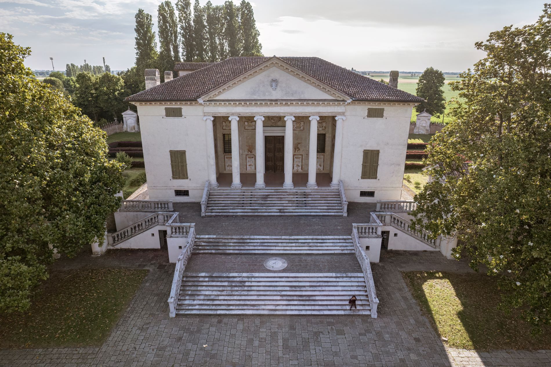 Pogled iz zraka na mogočno glavno stopnišče in vhod v Palladijevo vilo Badoer v Italiji s stebri, ki spominja na pročelje antičnega templja.