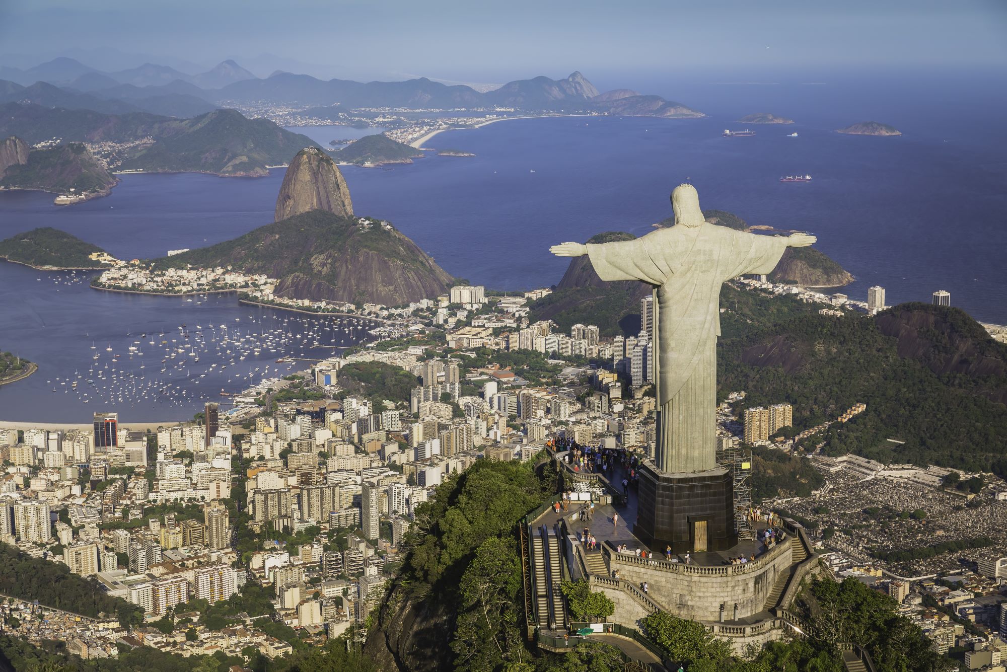 Pogled na kozmopolitsko brazilsko mesto Rio de Janeiro s kipom Kristusa odrešenika na razglednem hribu Corcovado in v ozadju znamenita vzpetina Sladkorni stožec.