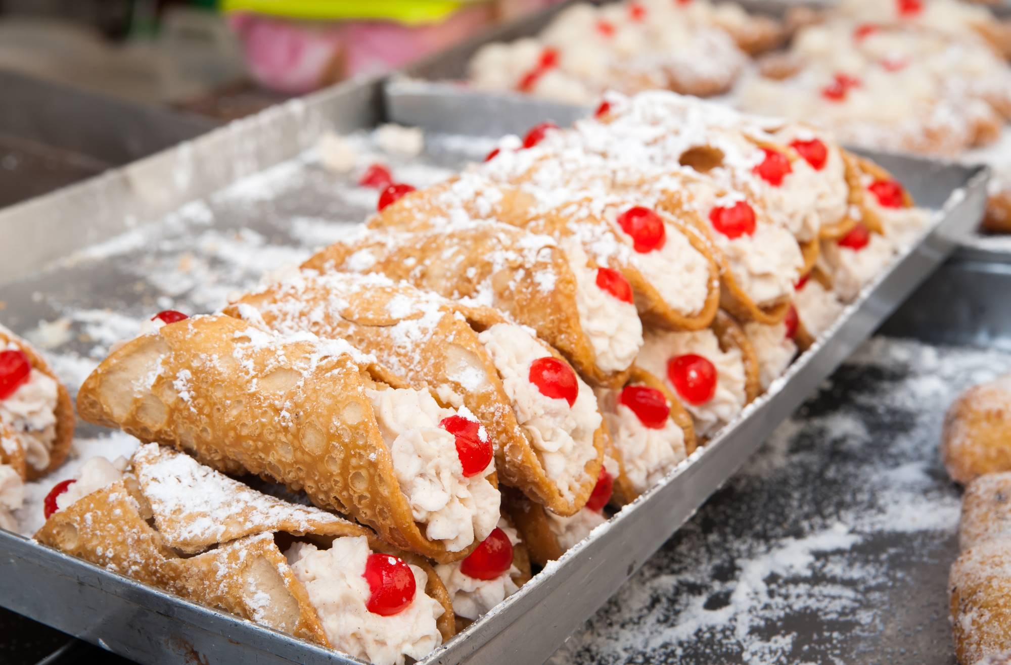 Slaščičarna z razstavljenimi slavnimi siciljanskimi sladicami cannoli iz ocvrtega testa, polnjena s s sladkim kremastim nadevom iz rikote.