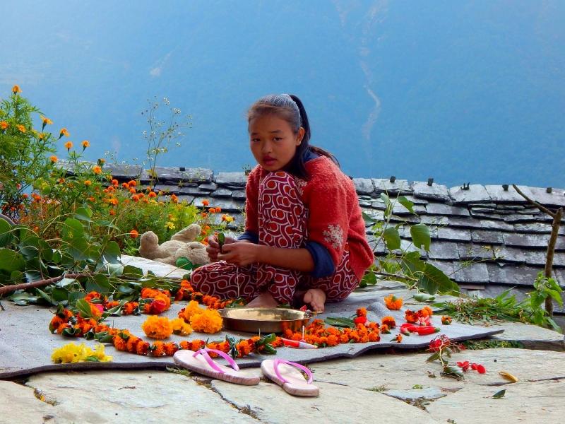 Mlada Nepalka pred enim od templjev prodaja okrasne rože.