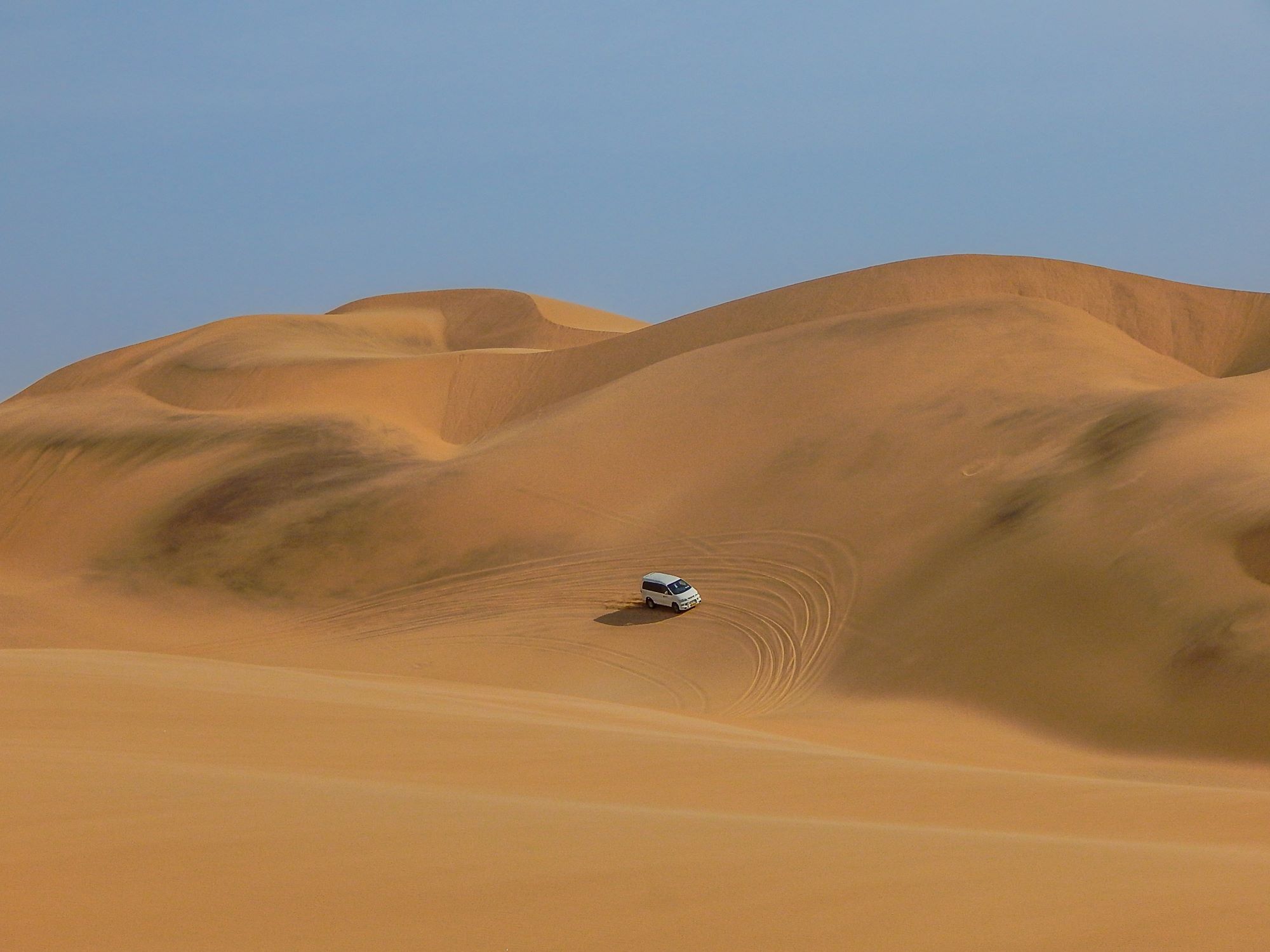 Terensko vozilo med vožnjo po sipini v puščavi Namib južno od kraja Swakopmund ob Atlantskem oceanu v Namibiji.